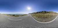 an empty mountain side road with a wide angle perspective of the road and a sunny sky