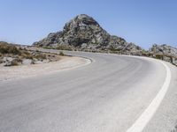 an empty mountain road next to the ocean with two red and white motorcycles parked on side