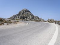 an empty mountain road next to the ocean with two red and white motorcycles parked on side