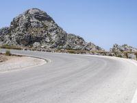 an empty mountain road next to the ocean with two red and white motorcycles parked on side