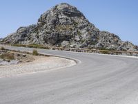 an empty mountain road next to the ocean with two red and white motorcycles parked on side