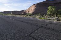 an empty empty paved mountain road in the desert with no traffic on it, and trees on both sides of the street