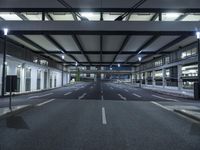 a street with empty lanes and lights is shown at night with no people around it