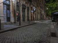 the street next to the tall building is empty and wet by night with signs indicating no sidewalks or people