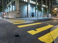 an empty street in the city at night with traffic lights on it and a tree