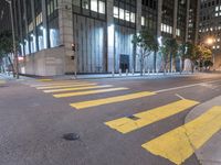 an empty street in the city at night with traffic lights on it and a tree