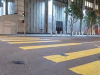 an empty street in the city at night with traffic lights on it and a tree