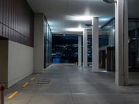 a walkway in an empty building with city skyline at night and clouds, behind it