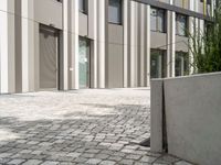 a large planter sits outside an empty building, with bricked ground next to it