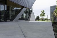 an empty concrete ground and a glassy building on a cloudy day with no people around