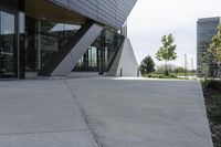 an empty concrete ground and a glassy building on a cloudy day with no people around