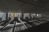 an empty office room with windows letting in sunlight and shadows all around it and on the floor