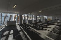 an empty office room with windows letting in sunlight and shadows all around it and on the floor