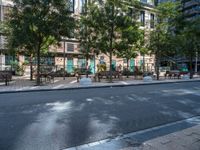 this is a view of an empty park area in a city setting where tables are on them, and one bench has a lamp