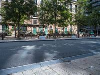 this is a view of an empty park area in a city setting where tables are on them, and one bench has a lamp