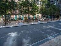 this is a view of an empty park area in a city setting where tables are on them, and one bench has a lamp