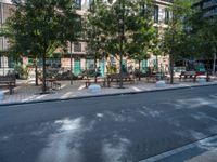 this is a view of an empty park area in a city setting where tables are on them, and one bench has a lamp