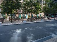 this is a view of an empty park area in a city setting where tables are on them, and one bench has a lamp