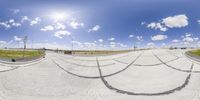 a fish eye view of an empty park near a road and grassy area, with no people on the ground