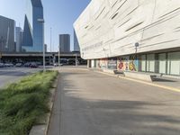 an empty parking area in front of a tall building with a blue sky behind it