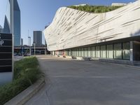 an empty parking area in front of a tall building with a blue sky behind it