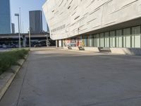 an empty parking area in front of a tall building with a blue sky behind it