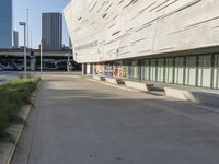 an empty parking area in front of a tall building with a blue sky behind it