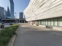 an empty parking area in front of a tall building with a blue sky behind it