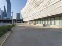 an empty parking area in front of a tall building with a blue sky behind it