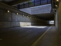 an empty parking area has lights illuminating it's side as a tunnel runs beneath the building