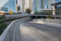 an empty parking area with cars and buildings in the background on a city street between a concrete wall and a sidewalk