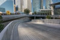 an empty parking area with cars and buildings in the background on a city street between a concrete wall and a sidewalk