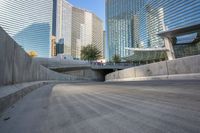 an empty parking area with cars and buildings in the background on a city street between a concrete wall and a sidewalk