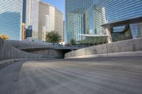 an empty parking area with cars and buildings in the background on a city street between a concrete wall and a sidewalk