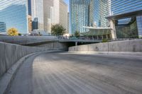 an empty parking area with cars and buildings in the background on a city street between a concrete wall and a sidewalk