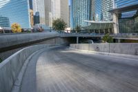 an empty parking area with cars and buildings in the background on a city street between a concrete wall and a sidewalk