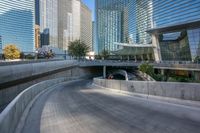 an empty parking area with cars and buildings in the background on a city street between a concrete wall and a sidewalk