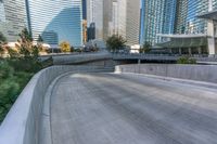 an empty parking area with cars and buildings in the background on a city street between a concrete wall and a sidewalk