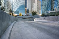 an empty parking area with cars and buildings in the background on a city street between a concrete wall and a sidewalk