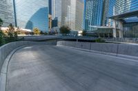 an empty parking area with cars and buildings in the background on a city street between a concrete wall and a sidewalk