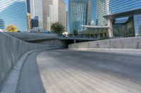 an empty parking area with cars and buildings in the background on a city street between a concrete wall and a sidewalk