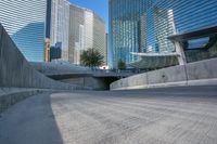 an empty parking area with cars and buildings in the background on a city street between a concrete wall and a sidewalk