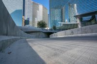 an empty parking area with cars and buildings in the background on a city street between a concrete wall and a sidewalk