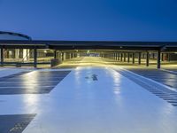 empty parking lot at night with light reflecting on floor and windows lit in front of building