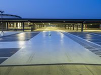 empty parking lot at night with light reflecting on floor and windows lit in front of building