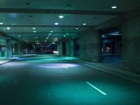 empty parking garage area with two rows of lights glowing on the ground, along with traffic in between