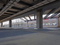 an empty open parking garage with multiple columns and benches under the overhead roof overhead, with one of the car