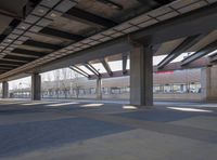 an empty open parking garage with multiple columns and benches under the overhead roof overhead, with one of the car