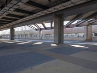 an empty open parking garage with multiple columns and benches under the overhead roof overhead, with one of the car