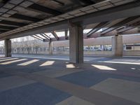 an empty open parking garage with multiple columns and benches under the overhead roof overhead, with one of the car